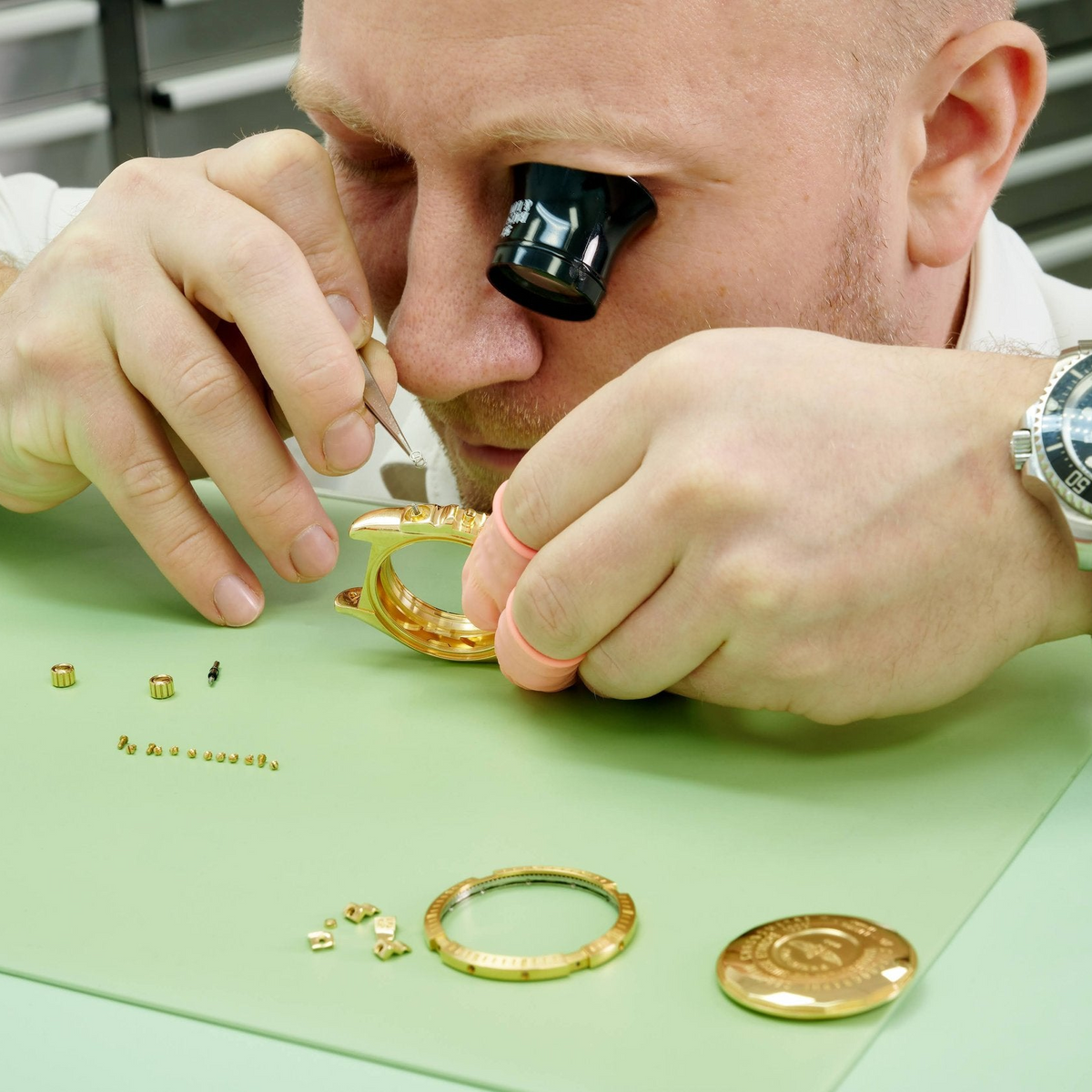 A technician inspecting a gold watch case