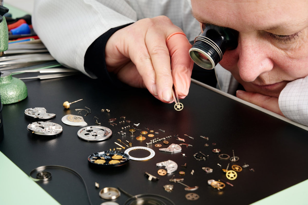 A technician inspects the individual parts of a watch