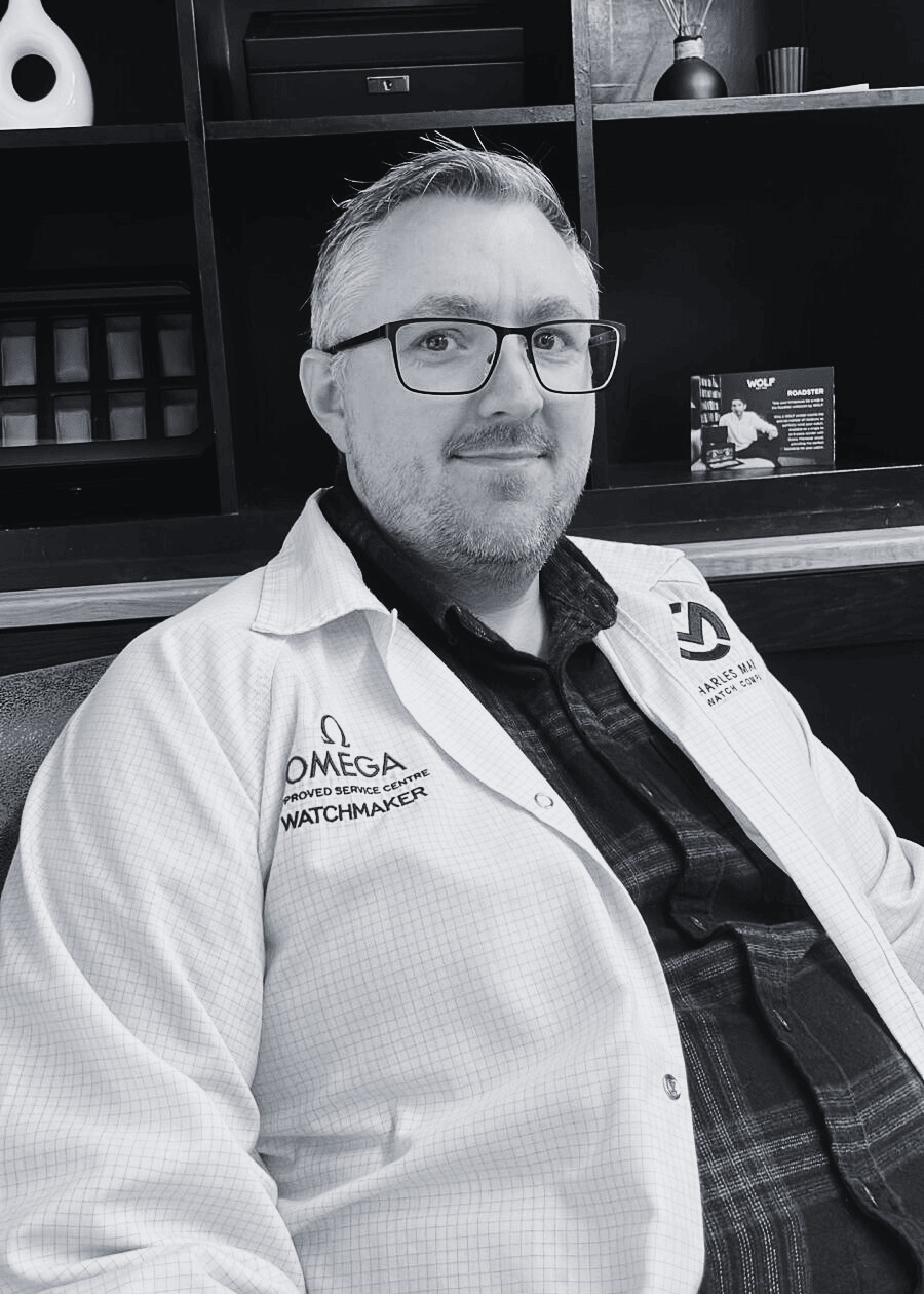 Person wearing a white coat with Omega branding in Charles Martin Watch Company workshop